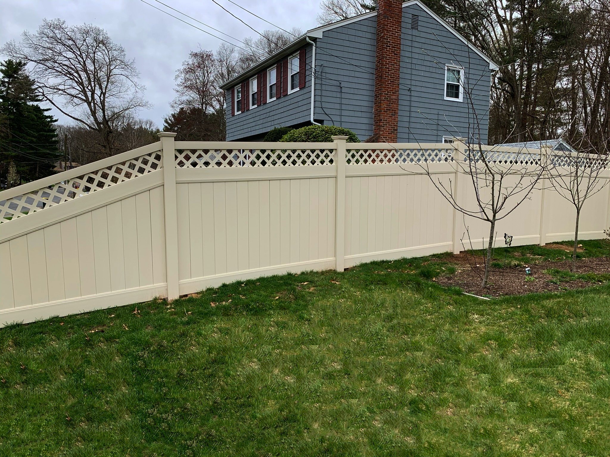 Tan vinyl privacy fence with decorative lattice top installed in New England