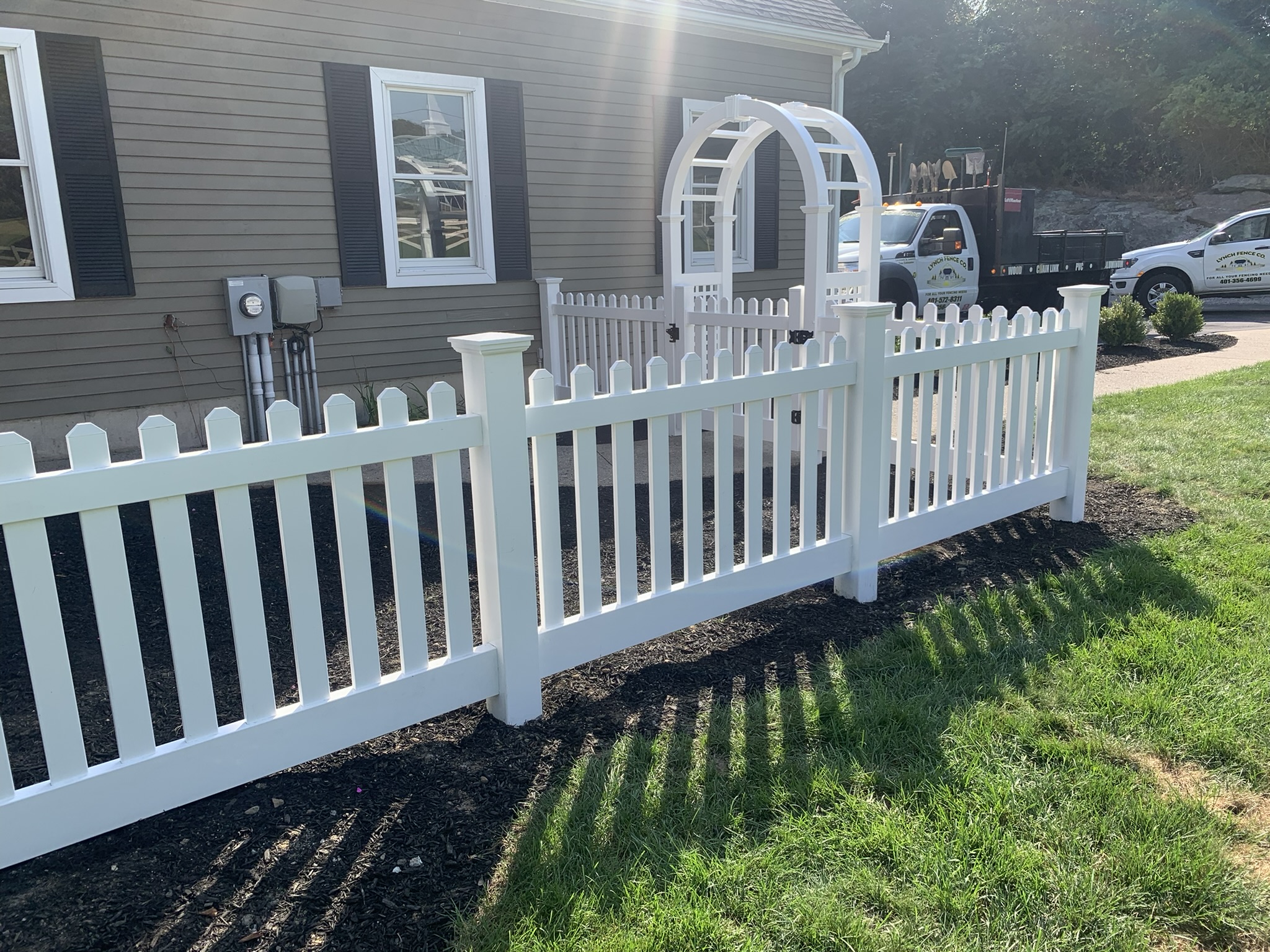 White vinyl picket fence with arbor gate installed by Lynch Fence Co Inc